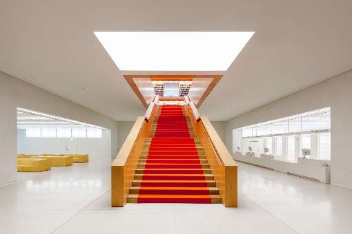 Foto 2: Die Haupttreppe der Bibliothek besticht durch den eleganten Kontrast von hellem Echtholzfurnier und orangener Wollfilzauflage. Foto: Staatsbibliothek zu Berlin - PK, J. F. Müller
